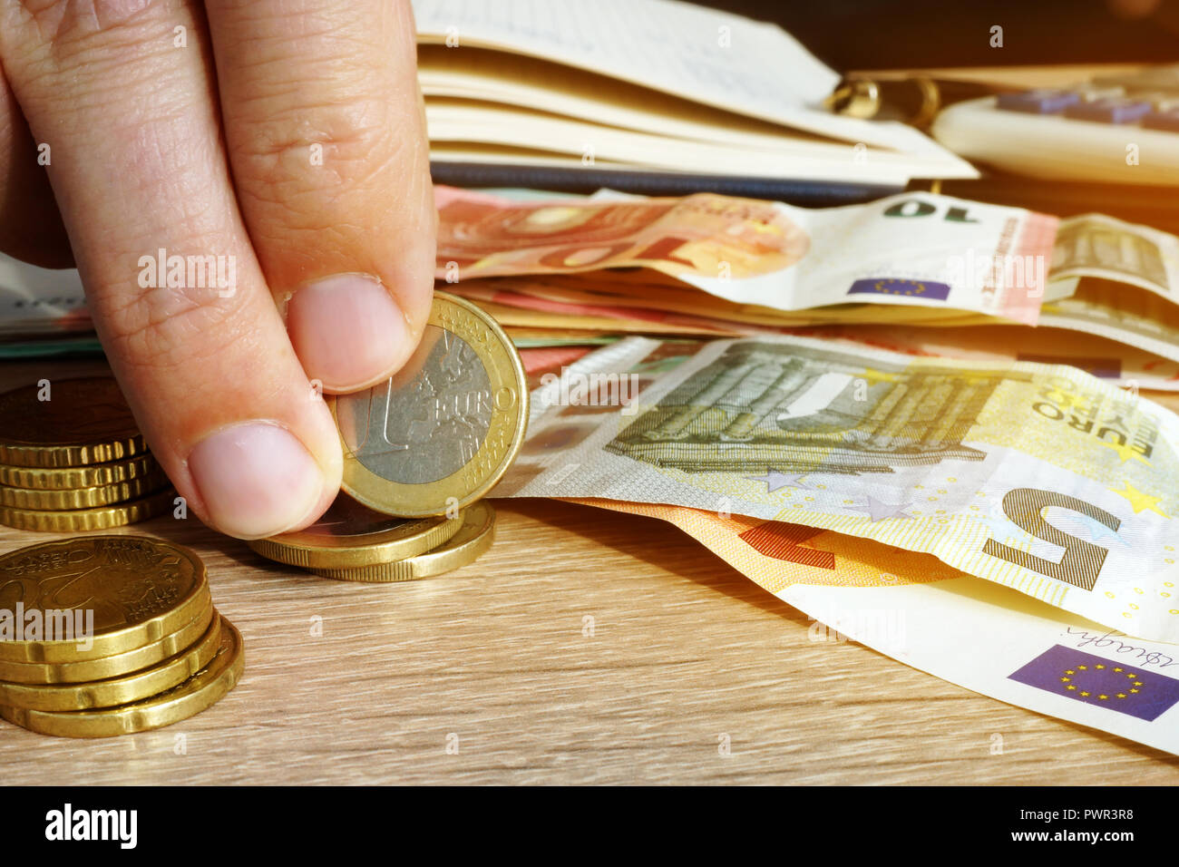 L uomo è azienda Euro monete e banconote su una scrivania. Risparmio. Foto Stock