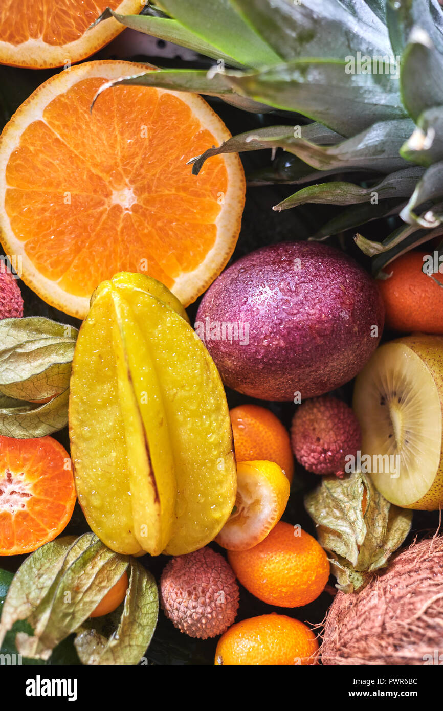 Organici naturali da sfondo frutti esotici carambole, mezza arancia, frutto della passione, foglia di ananas in gocce di acqua. Close-up. Foto Stock