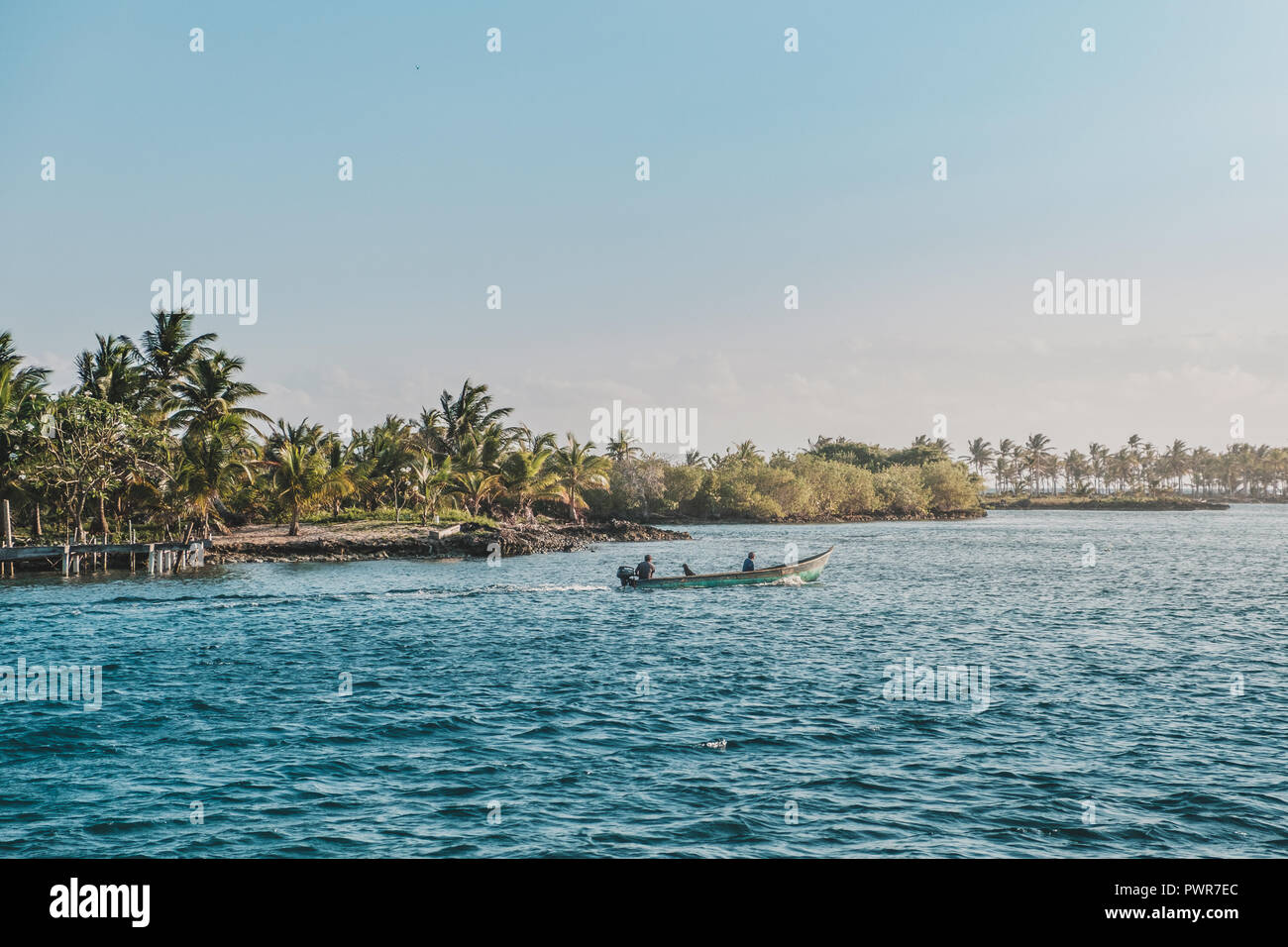 Due persone in piccolo motoscafo in oceano tropicale con Palm tree island paesaggio, Foto Stock