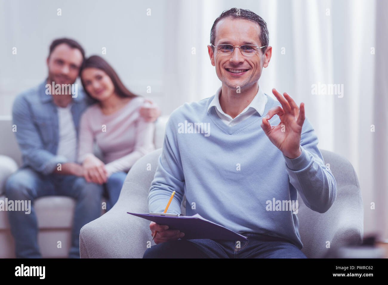 Allegro psicologo facendo un cerchio con il pollice e il dito indice Foto Stock
