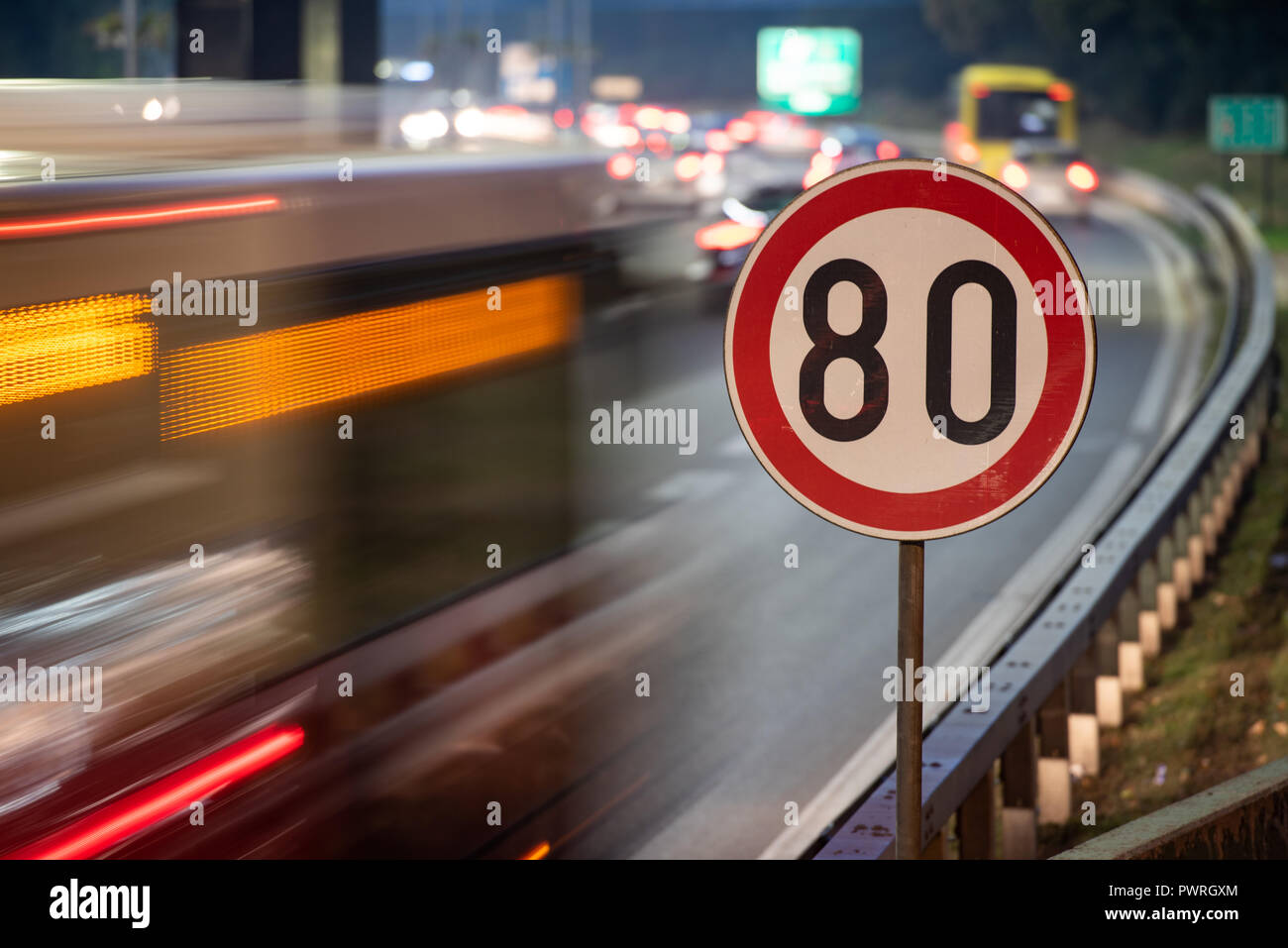 Una lunga esposizione colpo di segno di traffico che mostra 80 km/h il limite massimo di velocità su una strada piena di automobili in motion blur durante la notte Foto Stock