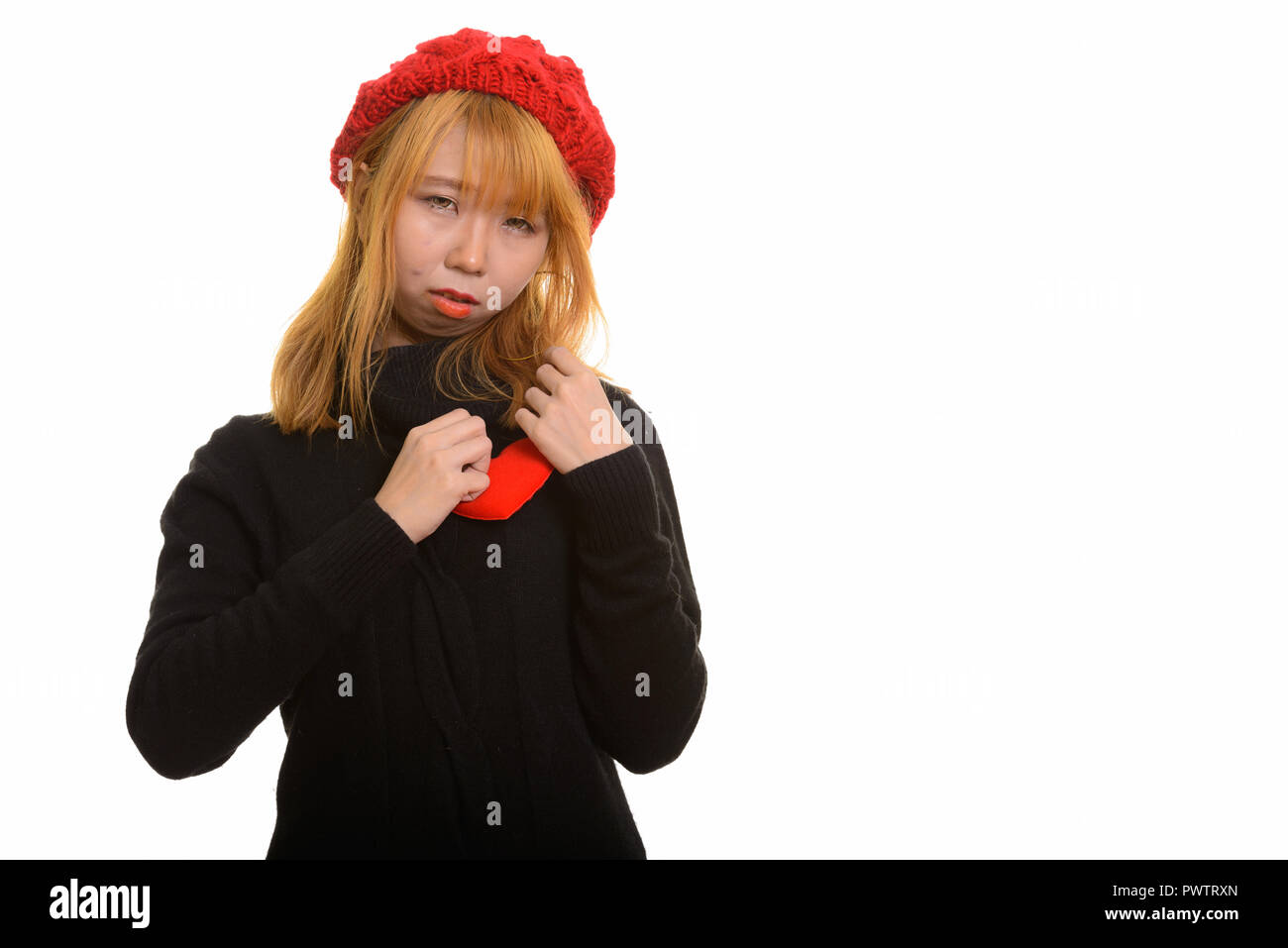 Giovani carino donna asiatica con cuore rosso sul petto guardando triste Foto Stock