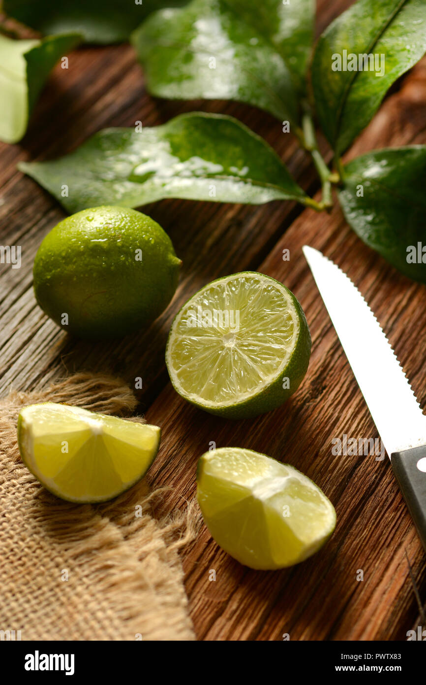 Lime frutti con foglie su un tavolo di legno - Frutta tropicali con proprietà antiossidanti - primo piano Foto Stock