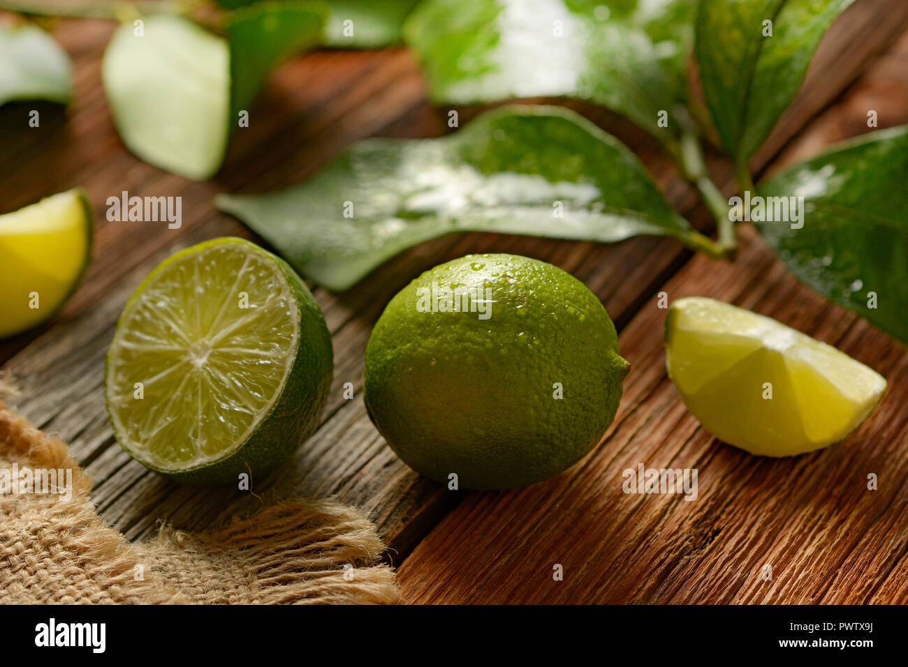 Lime frutti con foglie su un tavolo di legno - Frutta tropicali con proprietà antiossidanti - primo piano Foto Stock