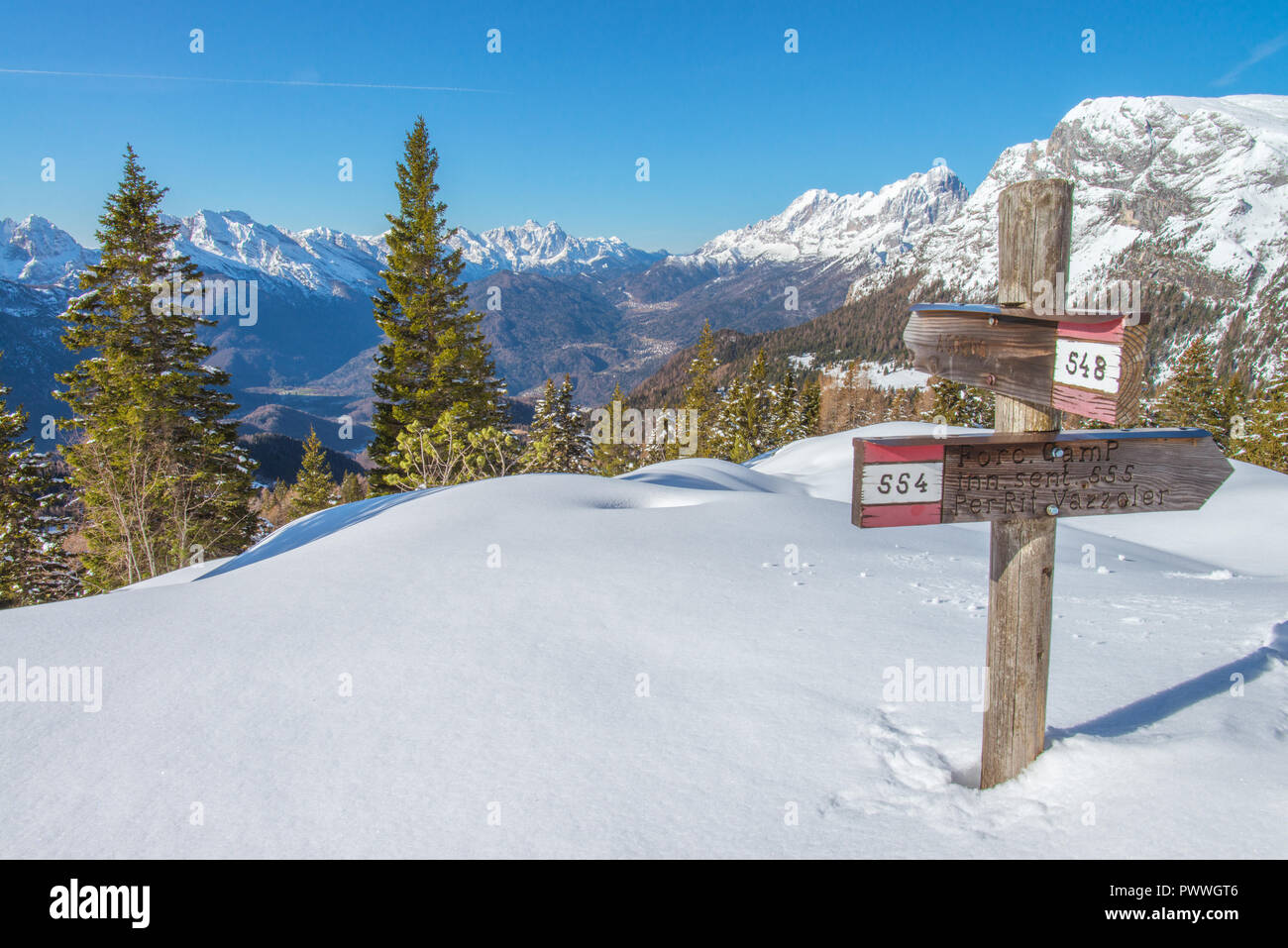 Segnavia, il cartello che indica la via verso i molti sentieri del sud delle Alpi italiane. Escursioni con le racchette da neve, le tracce sulla neve, giorno senza nuvole. Foto Stock