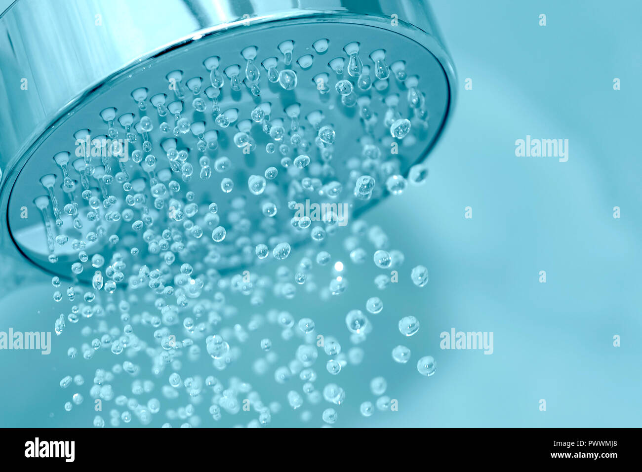 Primo piano della testa di doccia con acqua di irrorazione, nei toni del blu foto. Foto Stock