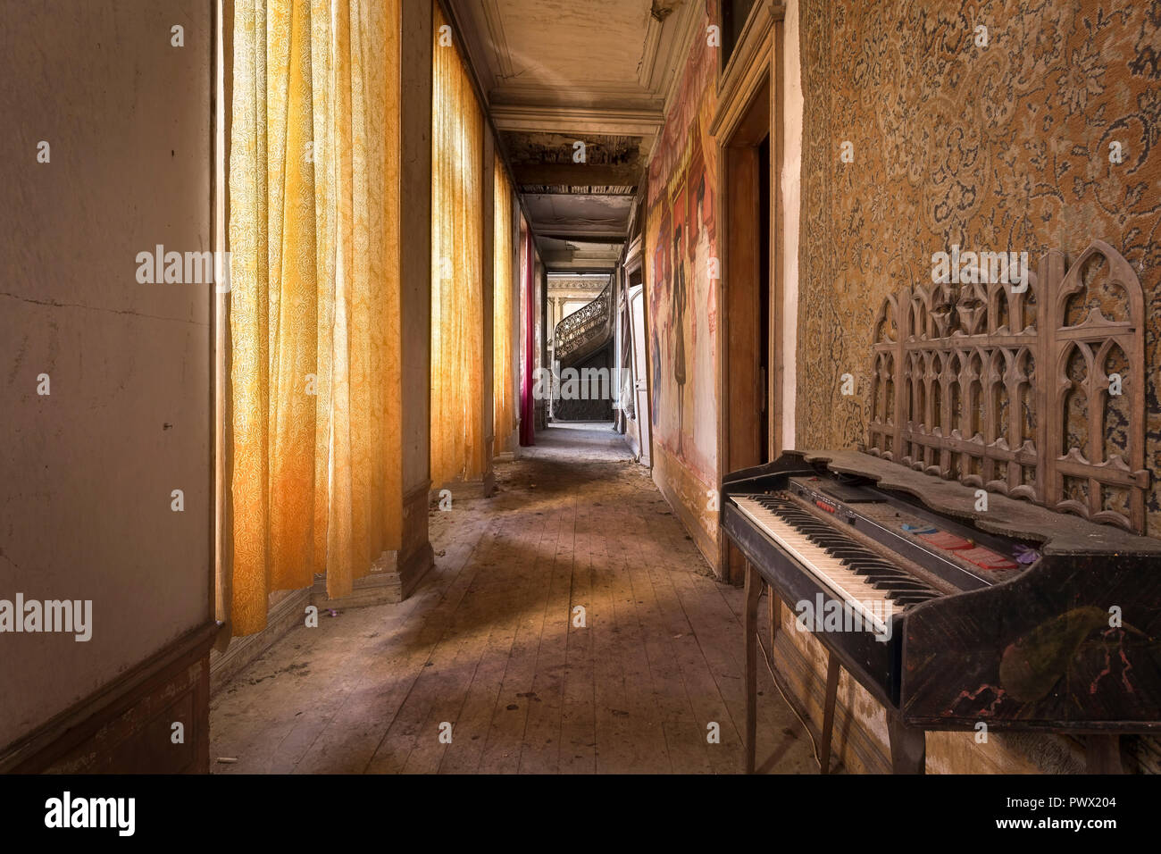 Vista interna di un corridoio con un pianoforte in un castello abbandonato in Francia. Foto Stock