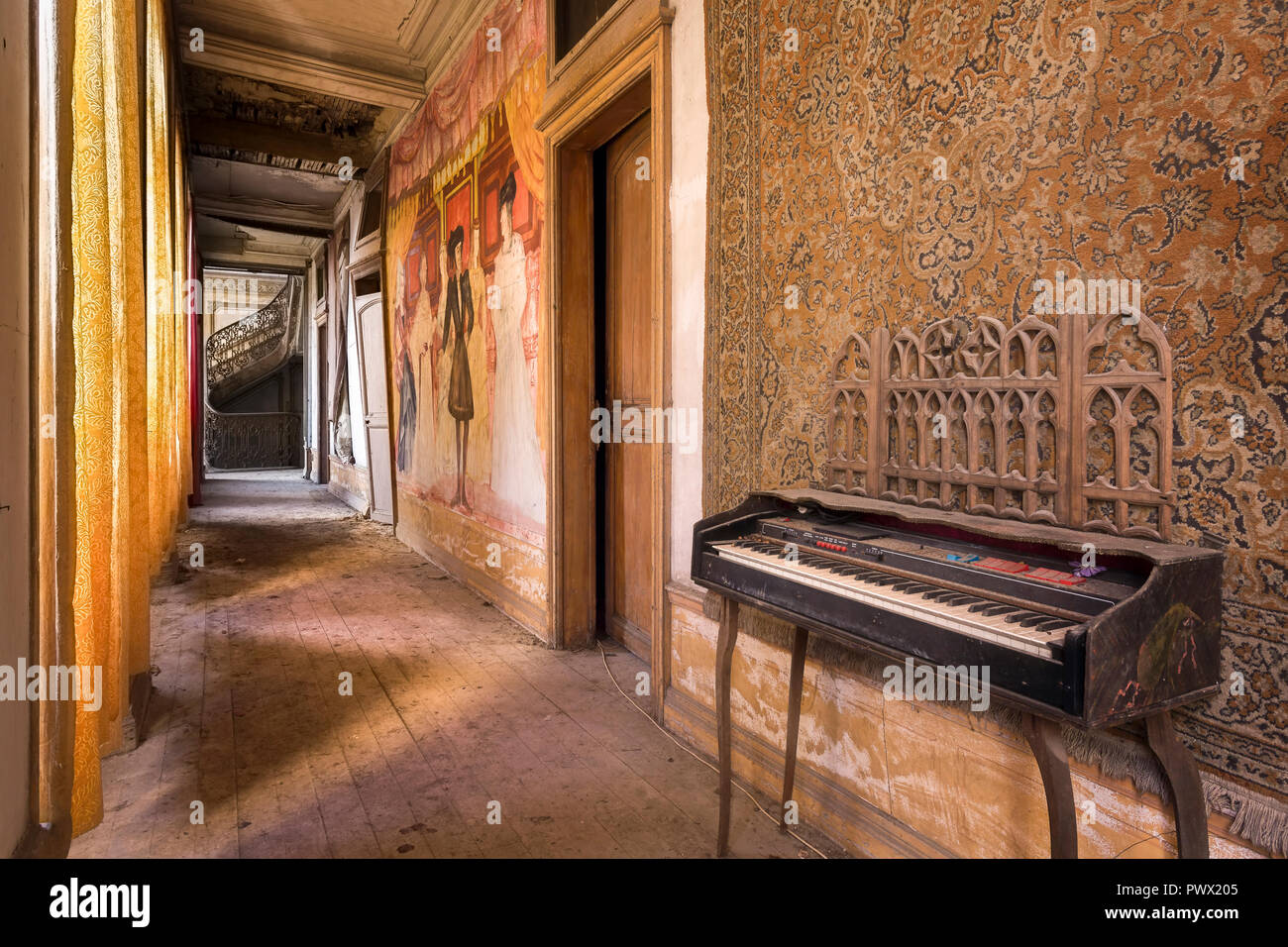 Vista interna di un corridoio con un pianoforte in un castello abbandonato in Francia. Foto Stock