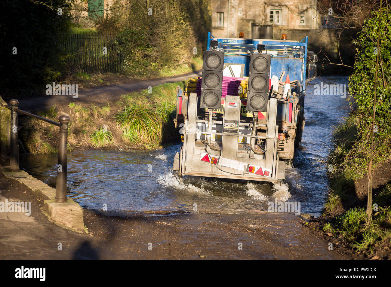 Una manutenzione stradale carrello attraversa una Ford nel villaggio di Lacock Wiltshire, Inghilterra REGNO UNITO Foto Stock