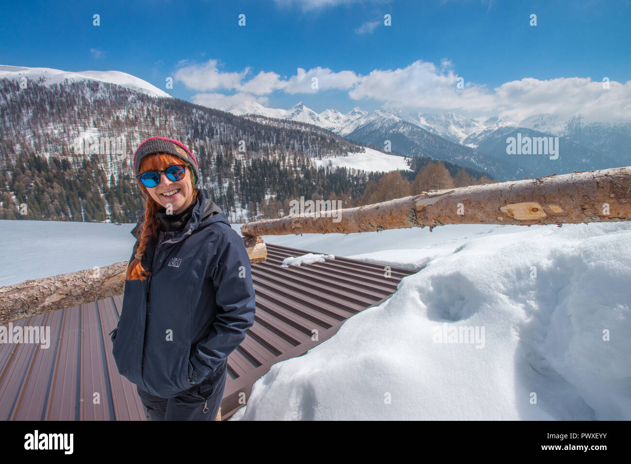 Felice escursionista in un Helly Hansen giacca sorridente dietro i suoi occhiali da sole. Viaggiatore godendo una giornata di escursioni con le racchette da neve sulla neve. Di polvere fresca di montagna. Foto Stock