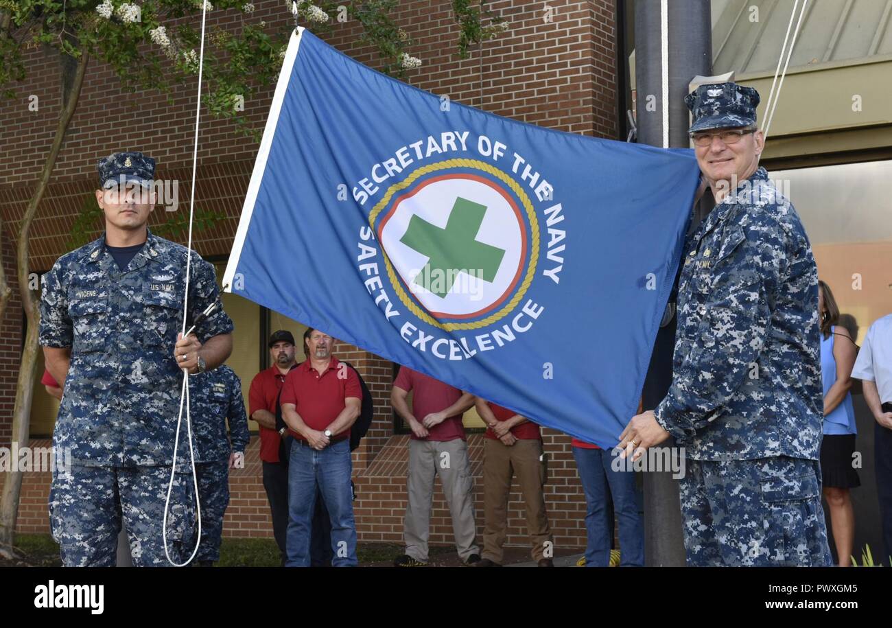 KINGS BAY, Ga. (30 giugno 2017)Capt. Gunter Braun, destra, comandante del Tridente riattaccare Facility Kings Bay, e agendo il comando Master Chief Antonio Vicens pronti per sollevare il segretario della Marina di eccellenza di sicurezza bandiera. Riattaccare Trident Facility è stato recentemente premiato con l'anno fiscale 2016 Sicurezza SECNAV Excellence Award per l'unità di terra della categoria. ( Foto Stock