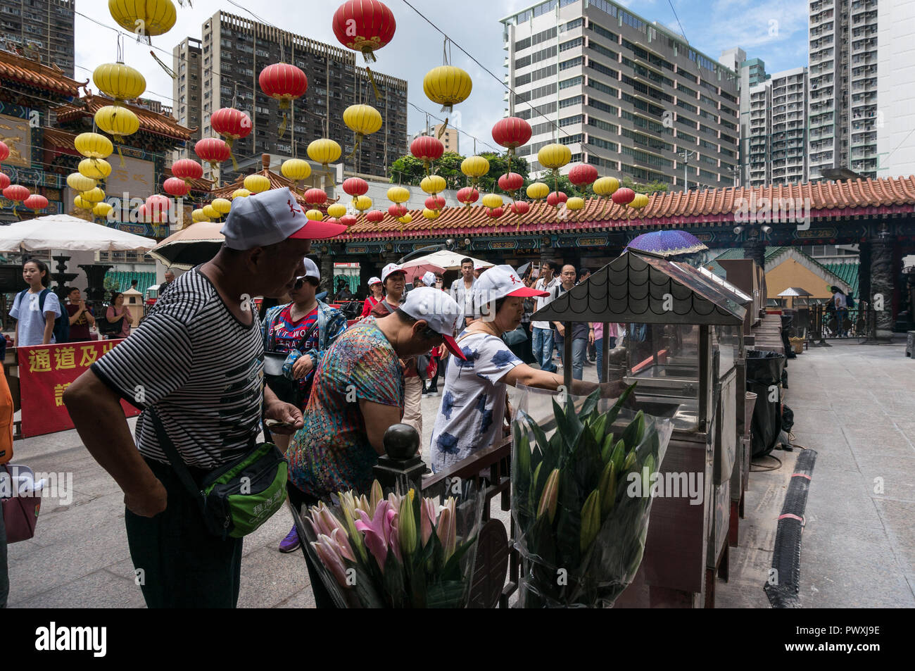 Anziani turisti cinesi che indossa il gruppo turistico cappelli augurio di buona fortuna come donare piccole somme a un tempio di scatole di donazione Foto Stock