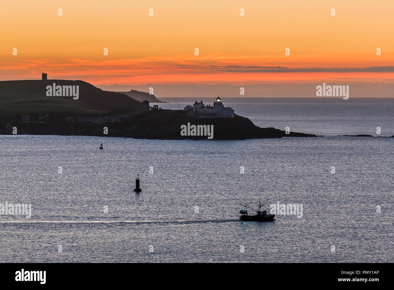 Roches Point, Cork, Irlanda. 18 ottobre, 2018. Una piccola barca da pesca di capi al di fuori del porto di Cork prima del sorgere del sole che passa la Roches Point Lighthouse, Co. Cork, Irlanda Credito: David Creedon/Alamy Live News Foto Stock