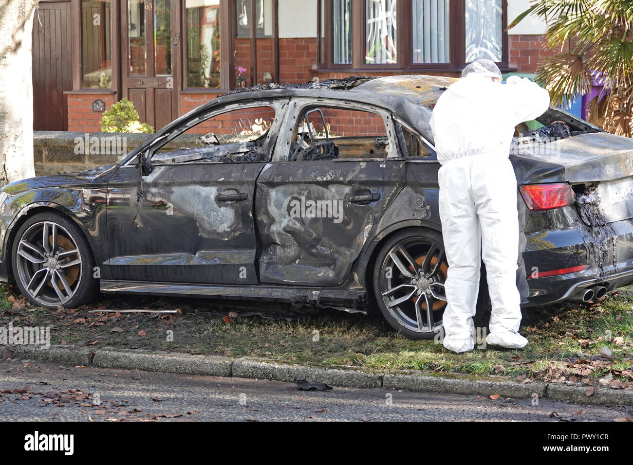 Liverpool, Regno Unito. Il 18 ottobre 2018. Un cordone di polizia attorno ad un bruciato auto in strada Abbeystead Childwall. Un colore scuro Audi abbandonate su un orlo di erba, 1.7 miglia da ultima notte di riprese in Alderson Rd, Wavertree. Un forensics officer è di scattare foto e la raccolta delle prove sulla scena. La polizia non sono dicendo in questa fase se la vettura è stata coinvolta in ultima notte di omicidio. Credito: Ken Biggs/Alamy Live News. Foto Stock