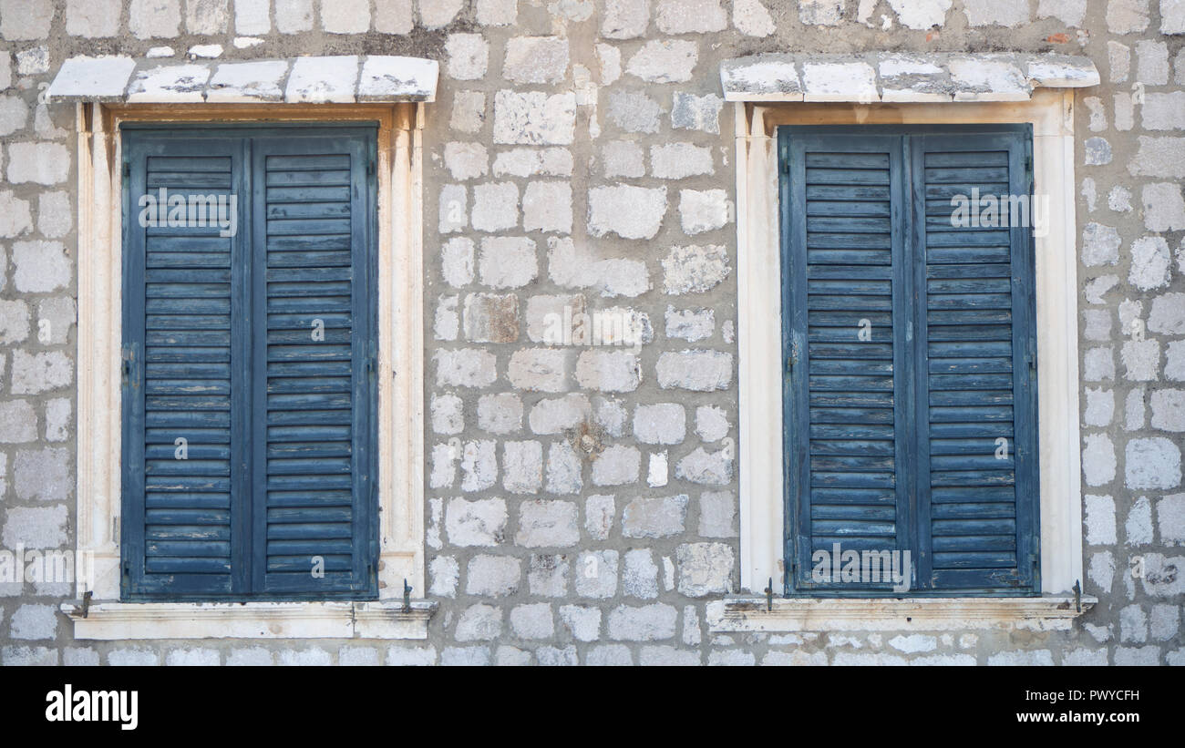 Due finestre nel vecchio muro chiuso con persiane blu Foto Stock