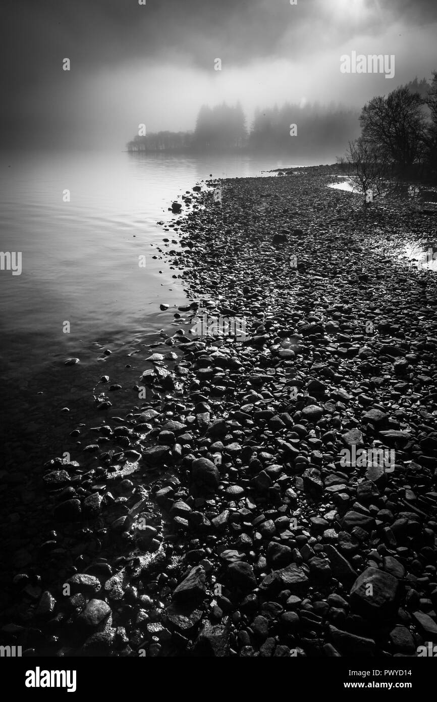 Una drammatica e nebbioso bordo di un loch in Scozia Foto Stock
