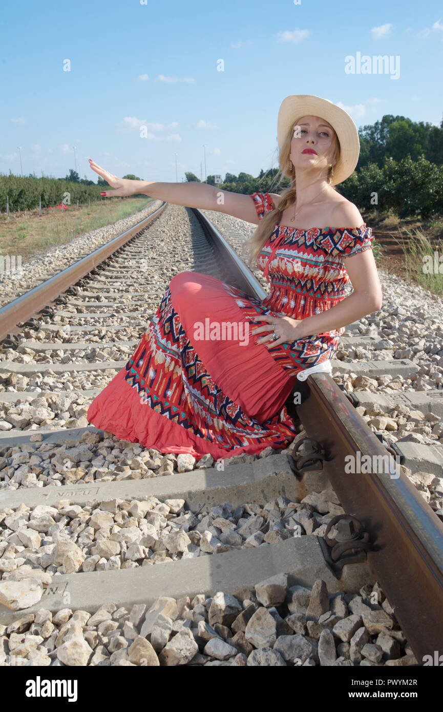 Una straordinaria giovane bionda signora attendere a locomotiva e provare a fermare il treno Foto Stock