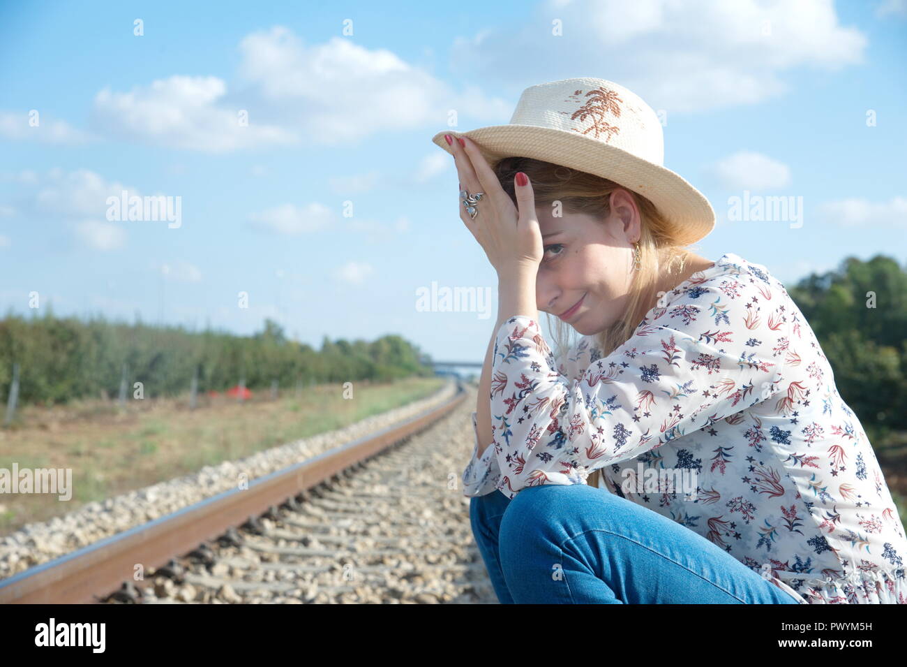 Una straordinaria giovane bionda signora attendere a locomotiva e provare a fermare il treno Foto Stock