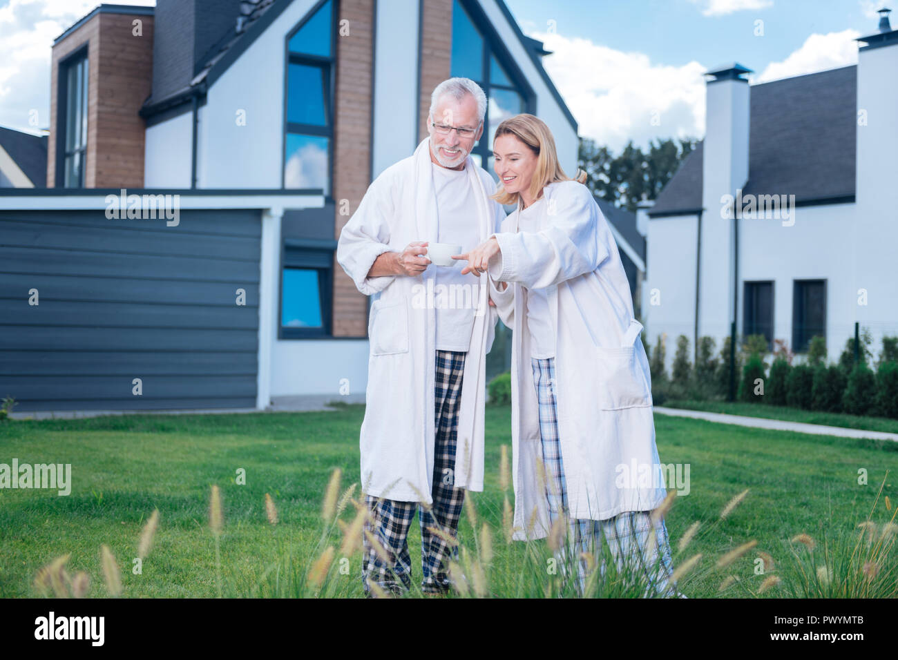 Coppia di imprenditori maturi indossando accappatoi camminare vicino a casa loro Foto Stock