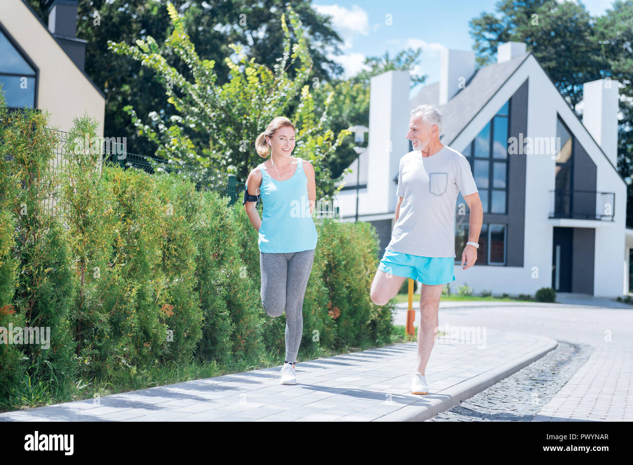 Coppia di imprenditori maturi stretching insieme dopo una lunga corsa mattutina Foto Stock