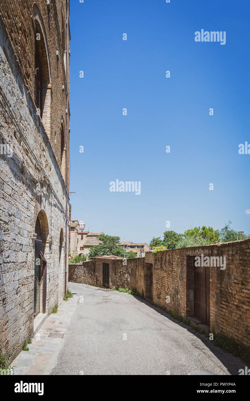 Foto verticale con pavimentazione a vuoto. Street si trova sul bordo della antica città di San Gimignano. La città è in Toscana - Italia. Il cielo sopra di vecchi edifici è cl Foto Stock