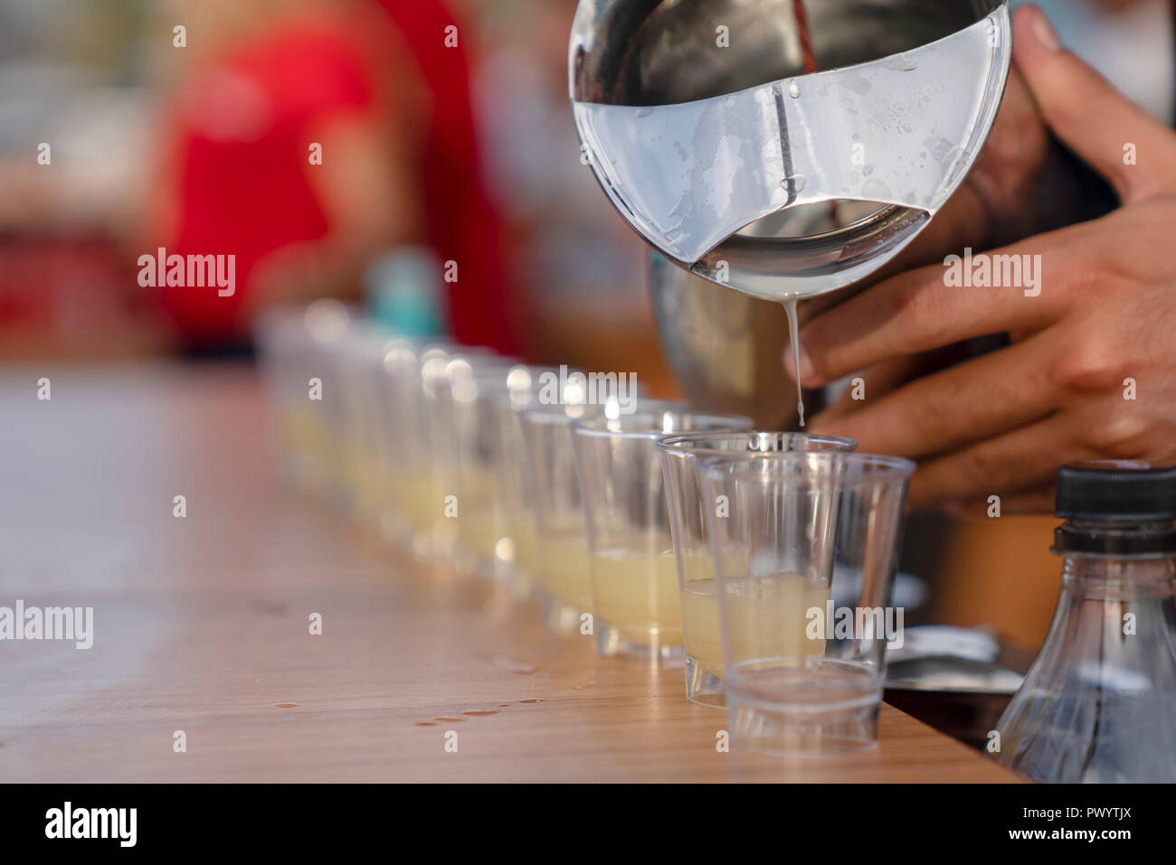 Versando bevanda alcolica in bicchierini in una riga Foto Stock