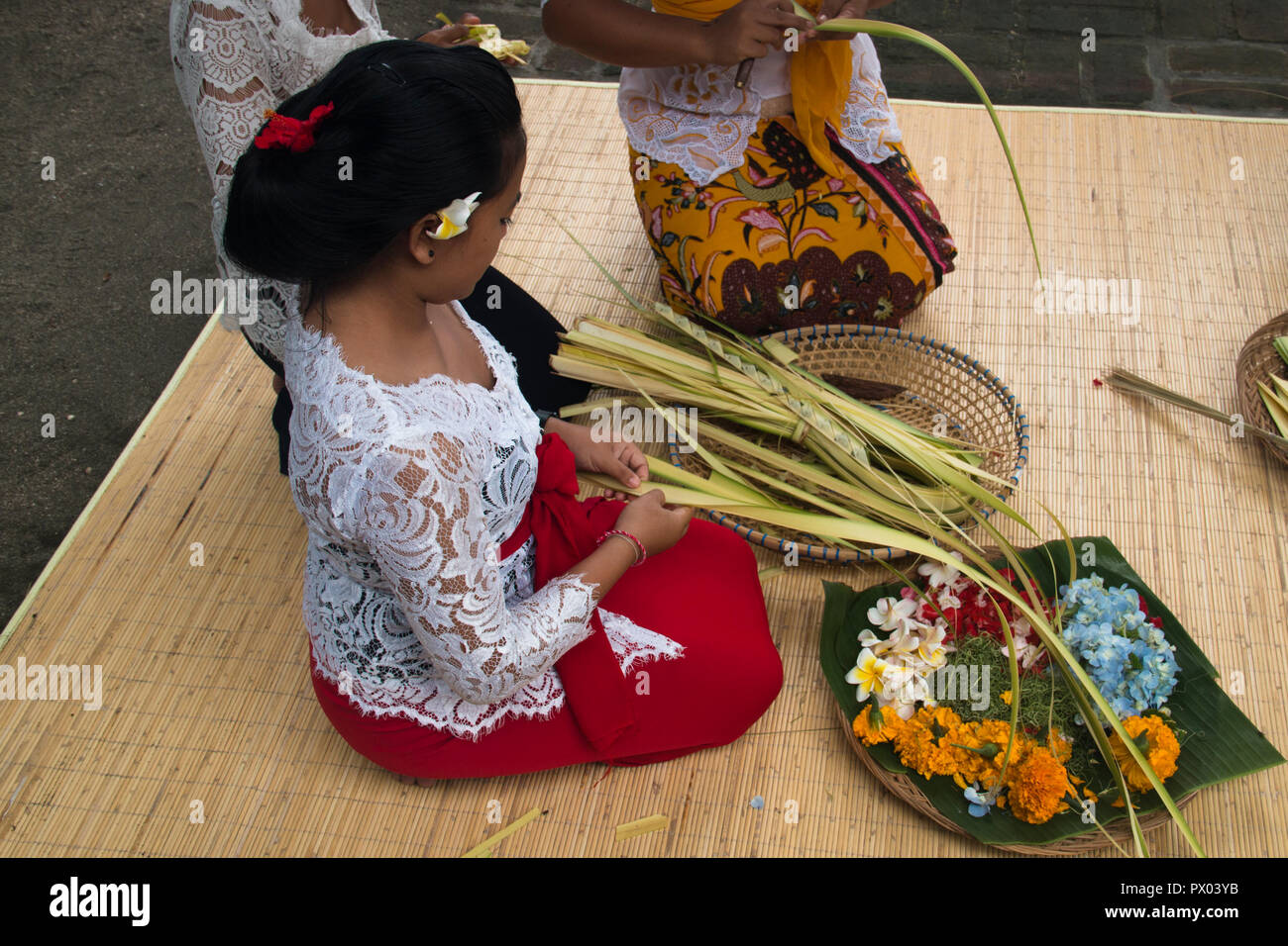 PEMUTERAN, BALI - Gennaio 2018: un gruppo di donne di Bali, Indonesia preparare le offerte giornaliere con cibo e fiori Foto Stock
