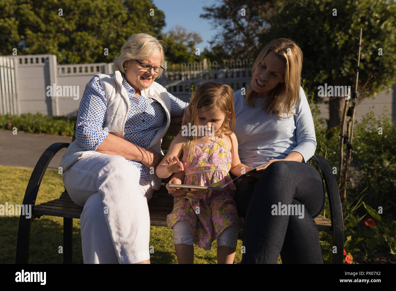 Multi-generazione famiglia guardando album di foto in giardino Foto Stock