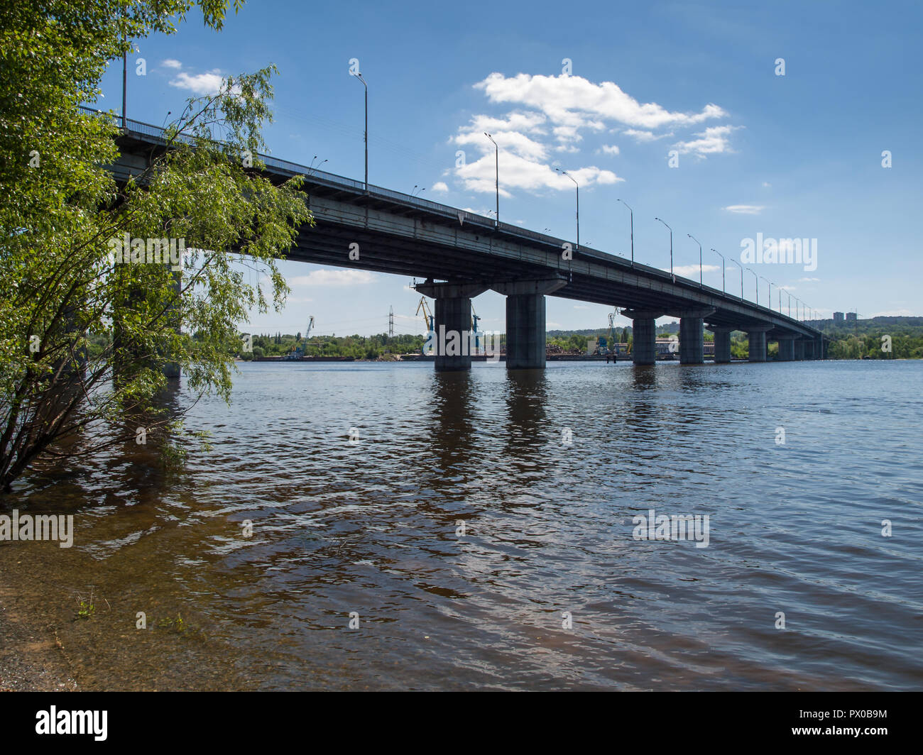 Lungo il ponte di calcestruzzo attraverso il grande fiume con il blu del cielo. Vista dal basso Foto Stock