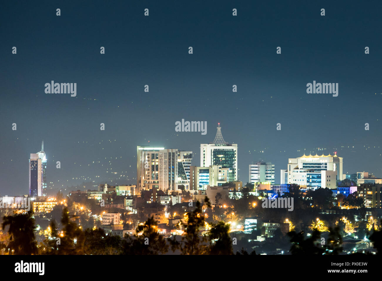 Un primo piano di Kigali skyline della città illuminata di notte, al di sotto di un profondo blu del cielo della sera Foto Stock