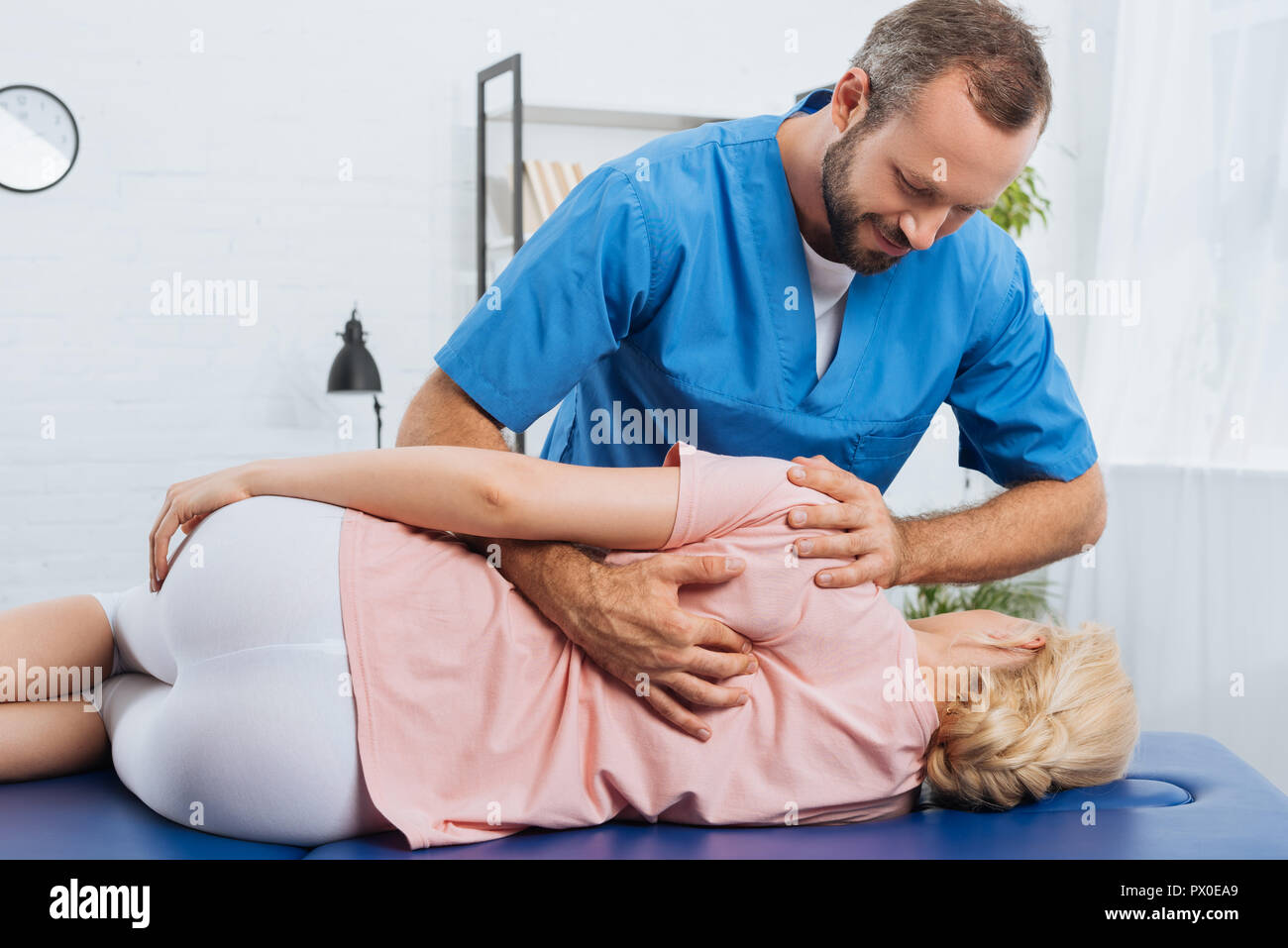Ritratto di sorridente massaggio chiropratico di schiena del paziente sdraiato sul lettino da massaggio in ospedale Foto Stock