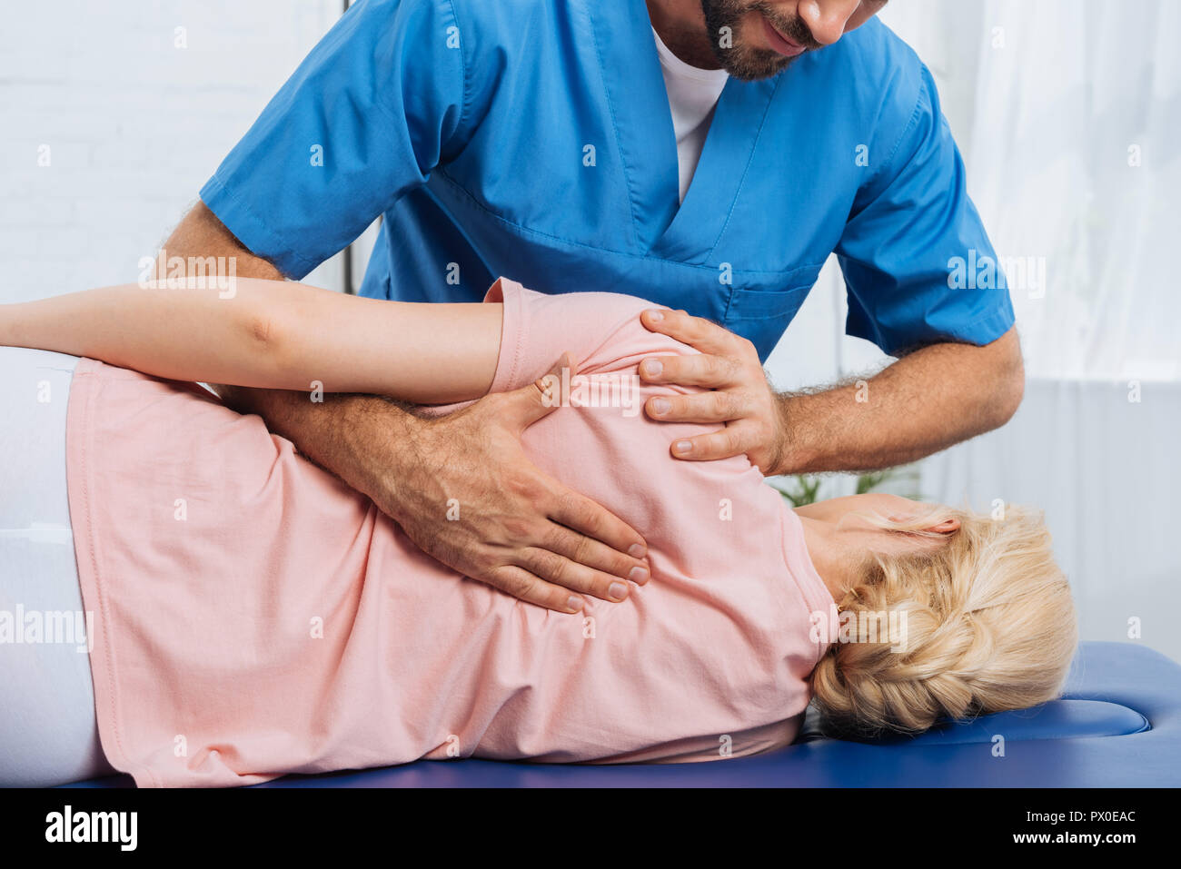 Ritagliato colpo di massaggio chiropratico di schiena del paziente sdraiato sul lettino da massaggio in ospedale Foto Stock