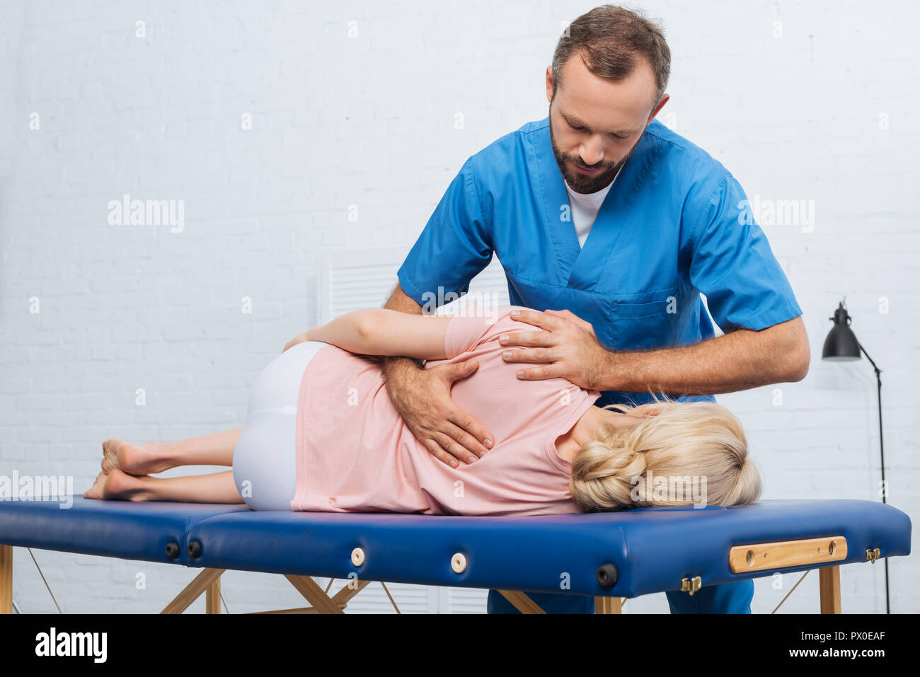 Ritratto di massaggio chiropratico di schiena del paziente sdraiato sul lettino da massaggio in ospedale Foto Stock