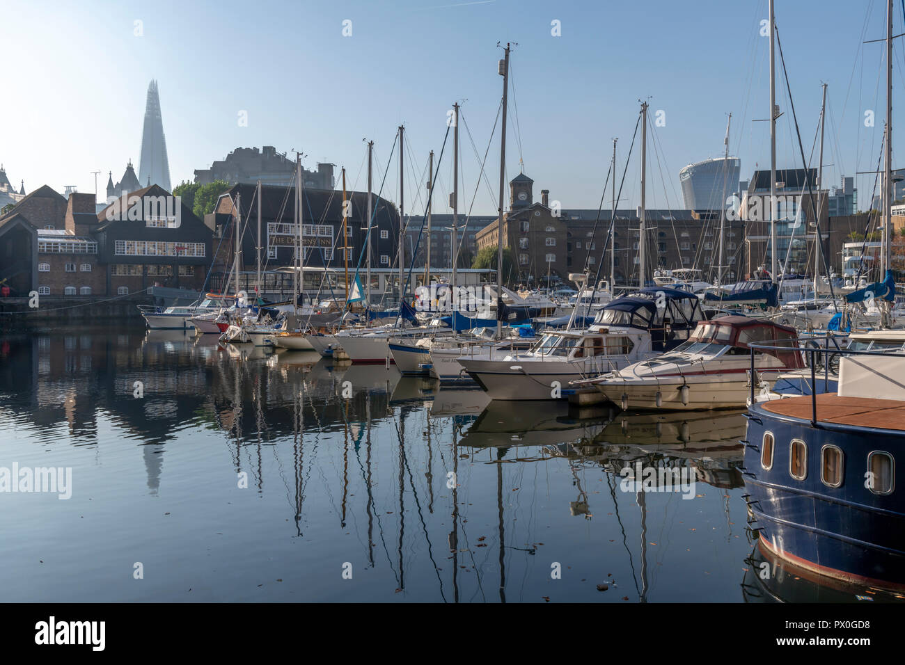 St Katherine's Dock Londra. Profondo cielo blu e riflessi nell'acqua che proviene dal Tamigi. Vicino al Tower Bridge è popolare con i turisti. Foto Stock