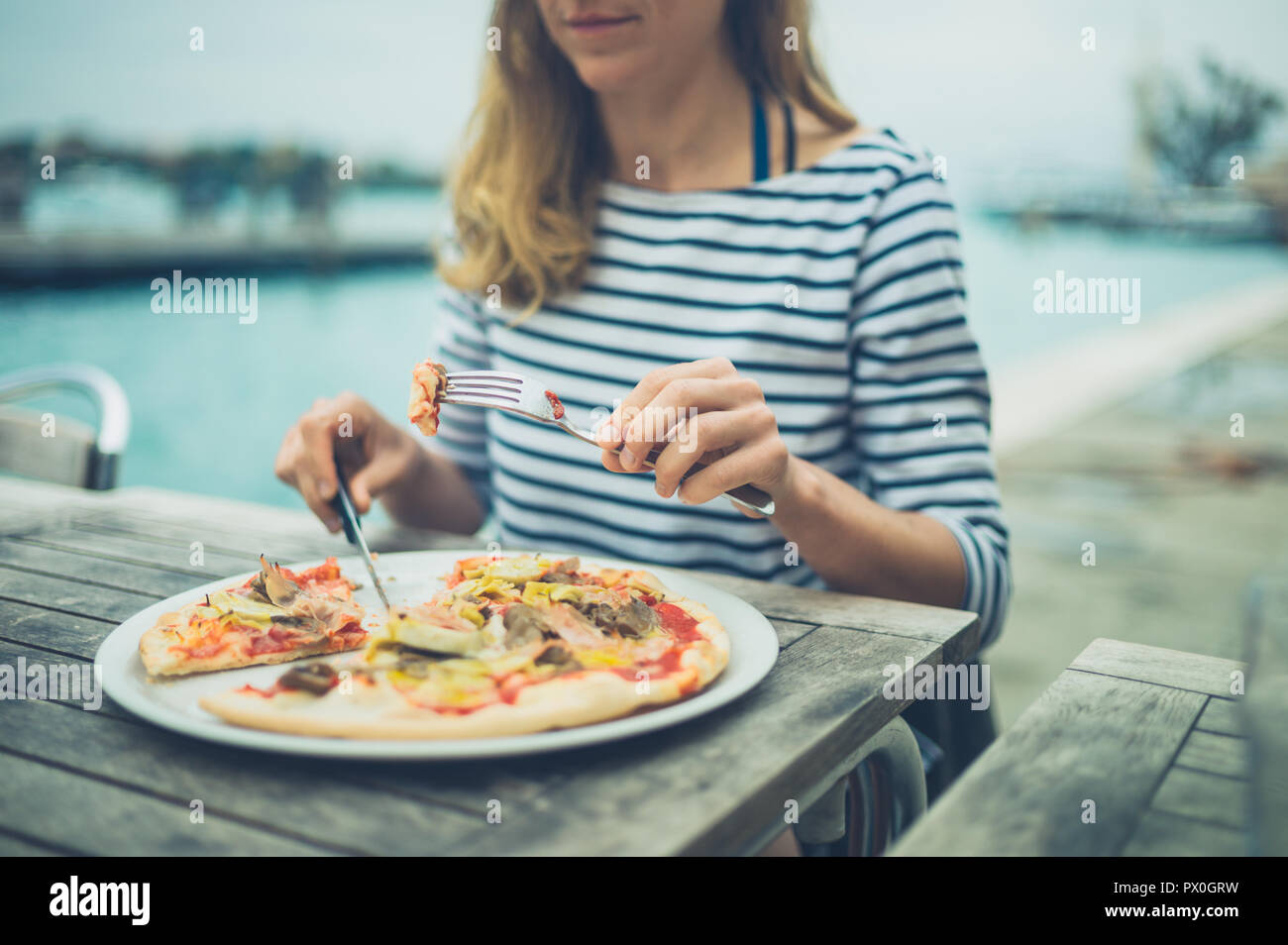 Una giovane donna è mangiare la pizza dal fiume Foto Stock