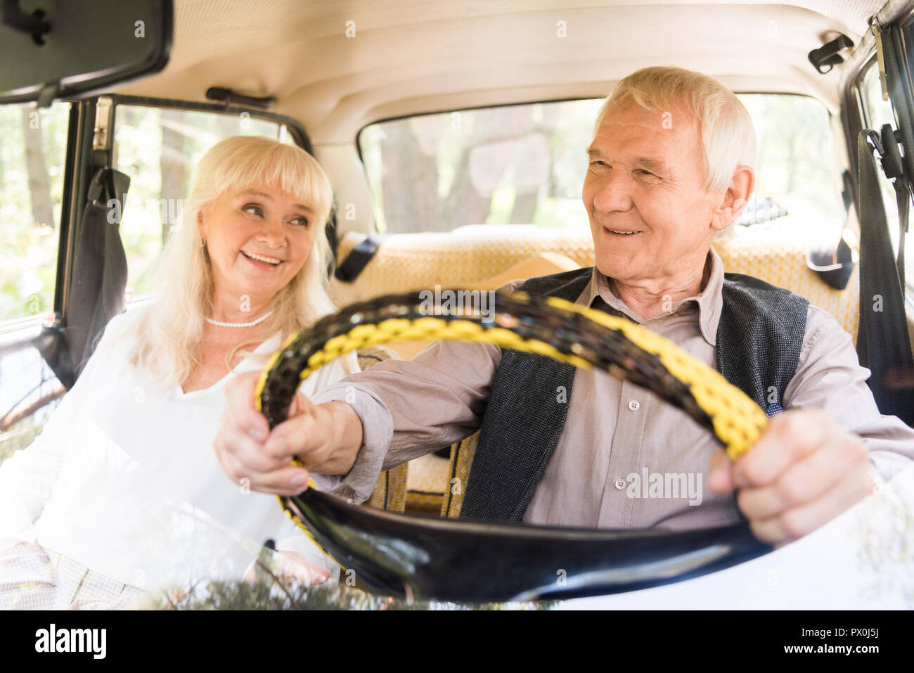 Bella coppia senior sorridente e la guida di auto di colore beige Foto Stock