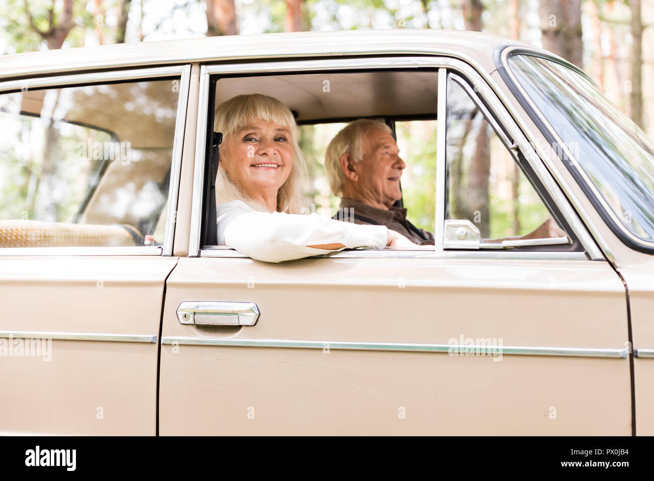 Vista laterale di sorridere coppia senior in auto di colore beige Foto Stock