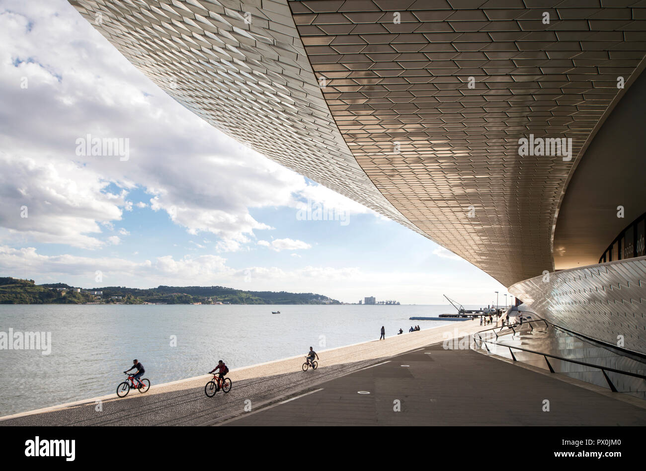 Vista esterna del MAAT - Museo di Arte, Architettura e Tecnologia, Lisbona, Portogallo. I ciclisti sulla terrazza sul fiume. Foto Stock