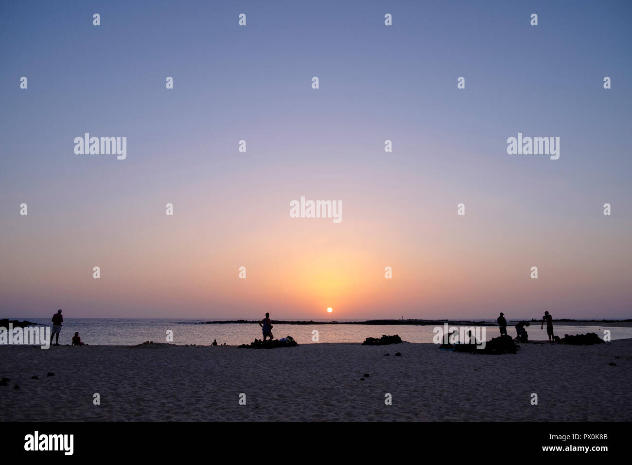 La gente guarda il tramonto dalla spiaggia Playa Chica vicino a El Cotillo, Fuerteventura. Foto Stock