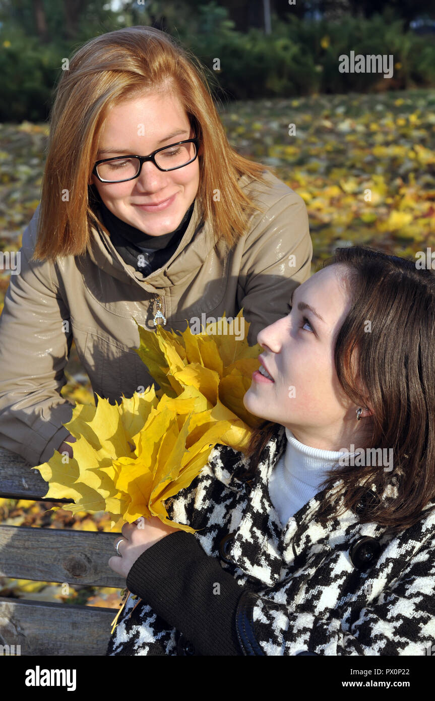 Due studentesse in appoggio in autunno park , in serie Foto Stock