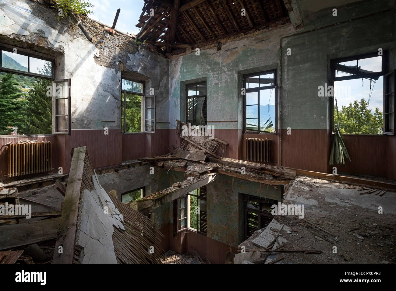 Vista interna di una camera con un foro nel pavimento in una scuola abbandonata in Italia. Foto Stock