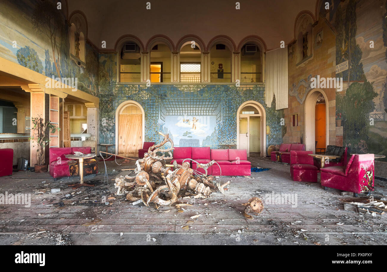 Vista interna di una camera in una discoteca abbandonata con una lampada a pavimento e divani rossi, in Italia. Foto Stock