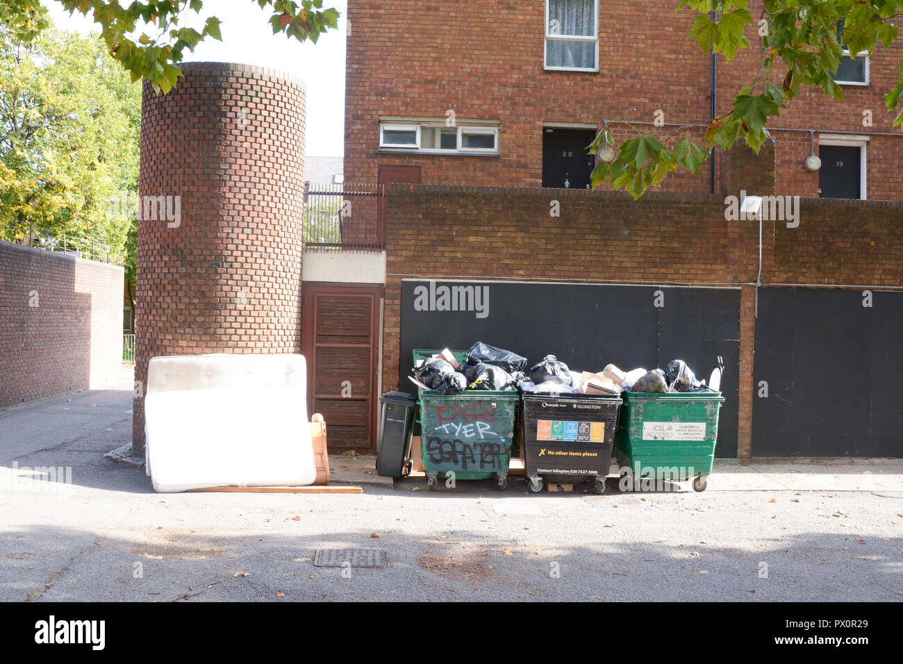 Piena bidoni della spazzatura e di altri rifiuti domestici compresi materassi al di fuori del blocco di appartamenti a Londra, Inghilterra Foto Stock