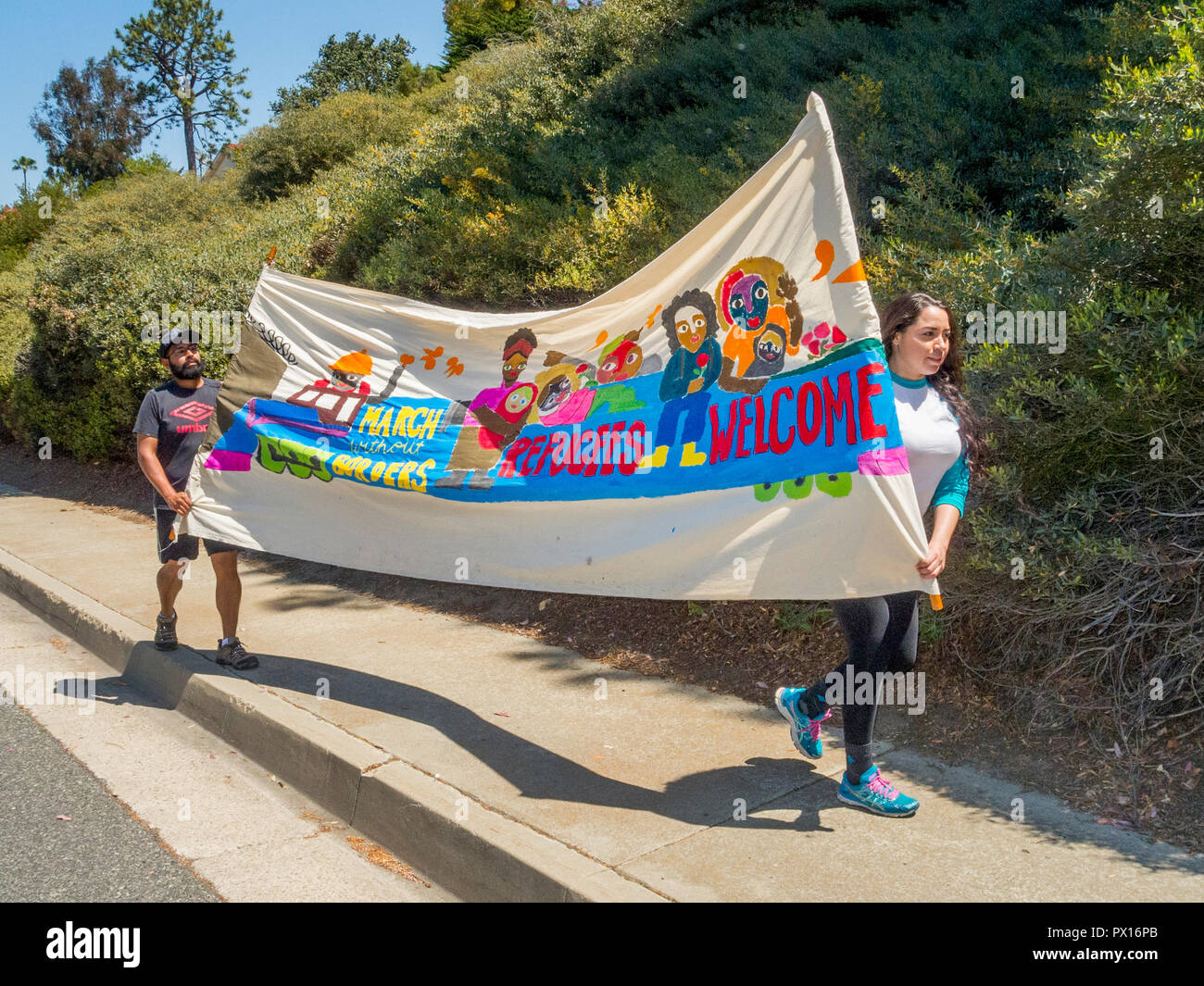 E multirazziale i giovani adulti portano un banner di proclamare "profughi" Benvenuto ad una politica liberale di dimostrazione in Laguna Beach, CA. Foto Stock