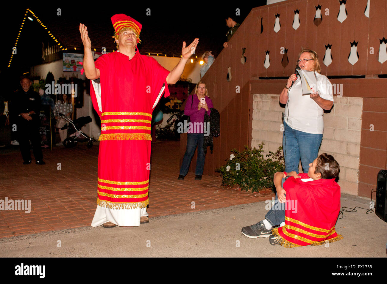 Un volontariato locale reenacts la storia di San Martino che dona la metà del suo mantello con un mendicante mentre un narratore che spiega la storia in una festa di Natale a Huntington Beach, CA. Foto Stock