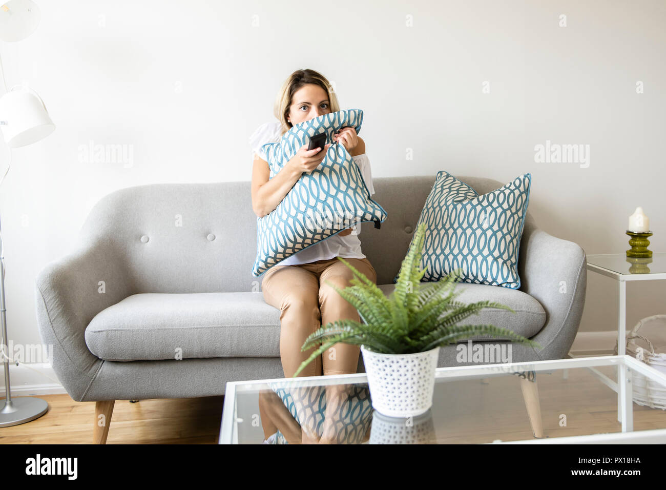 Le donne a guardare la TV sul divano di casa con il telecomando Foto Stock