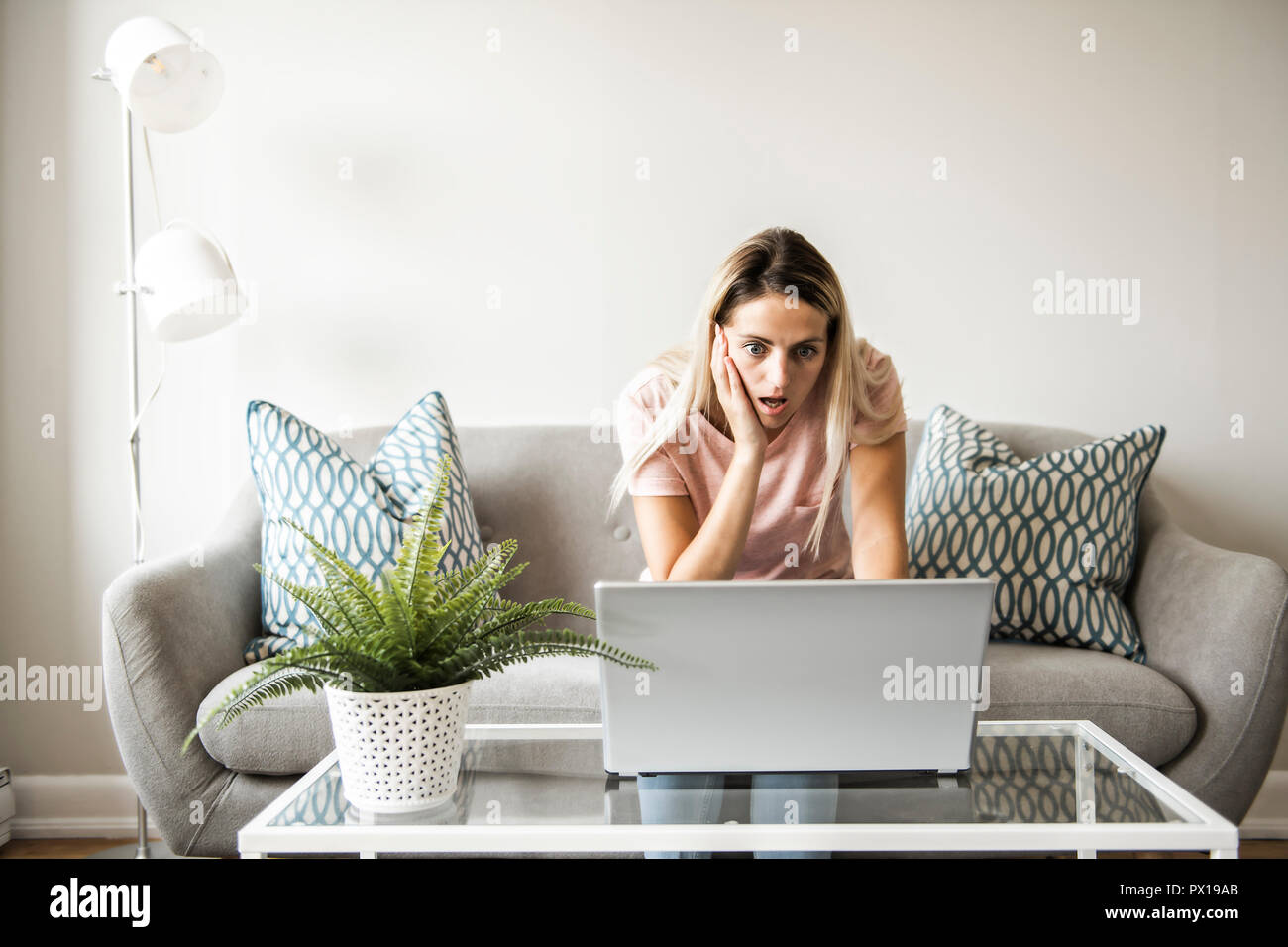 Donna con un computer portatile sul divano di casa Foto Stock