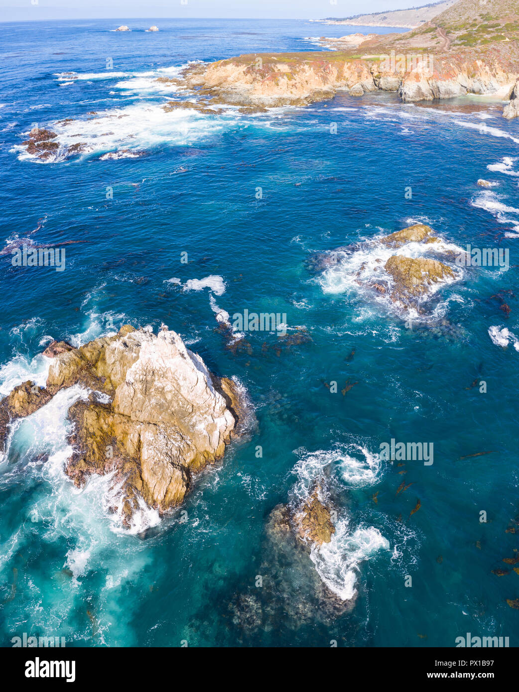 Il freddo, nutriente-ricco acque dell'Oceano Pacifico swirl contro il roccioso e paesaggistica costa della California del Nord non lontano da Monterey. Foto Stock