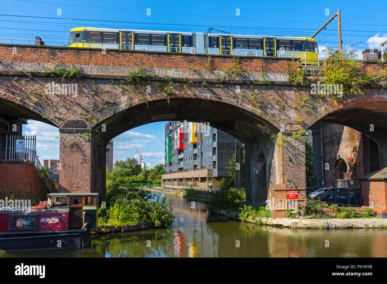 Tram Metrolink sul Vittoriano di un ponte ferroviario al pontile di patate su Bridgewater Canal a Castlefield, Manchester, Inghilterra, Regno Unito Foto Stock