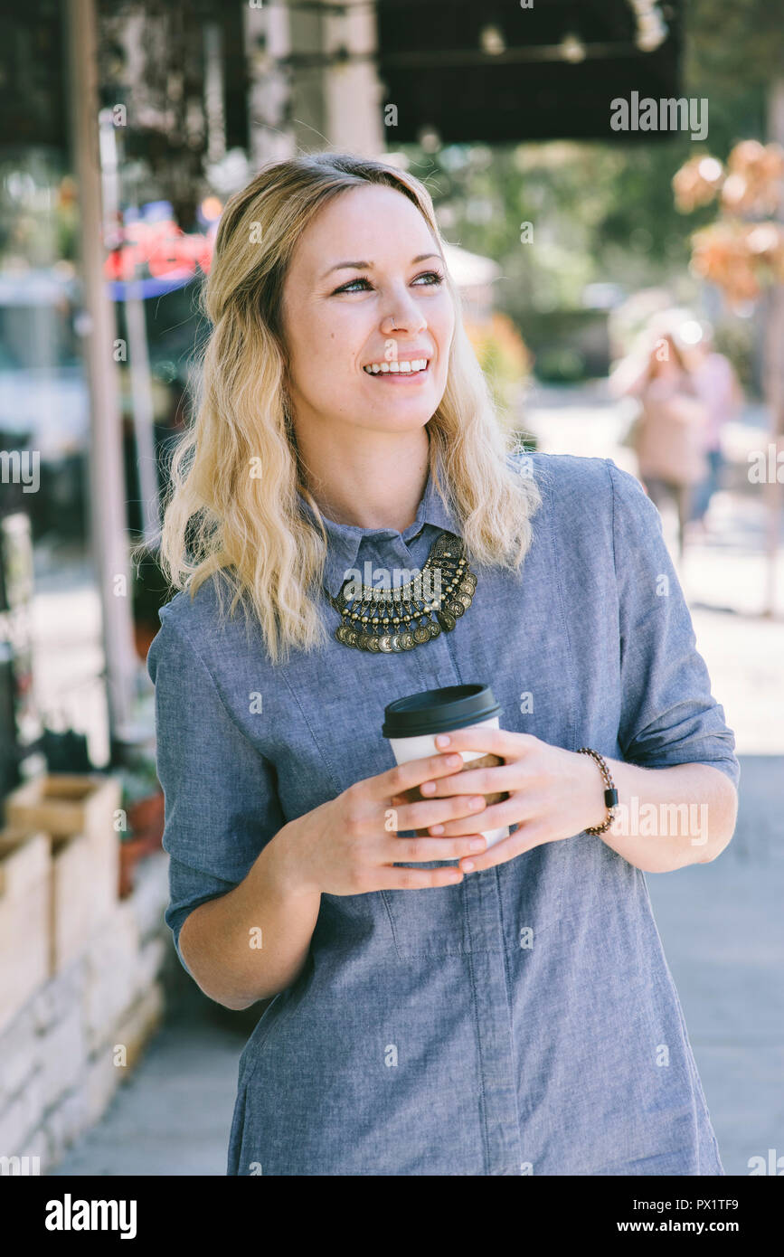 Felice ragazza millenario sorseggiando caffè all'aperto nella città Foto Stock